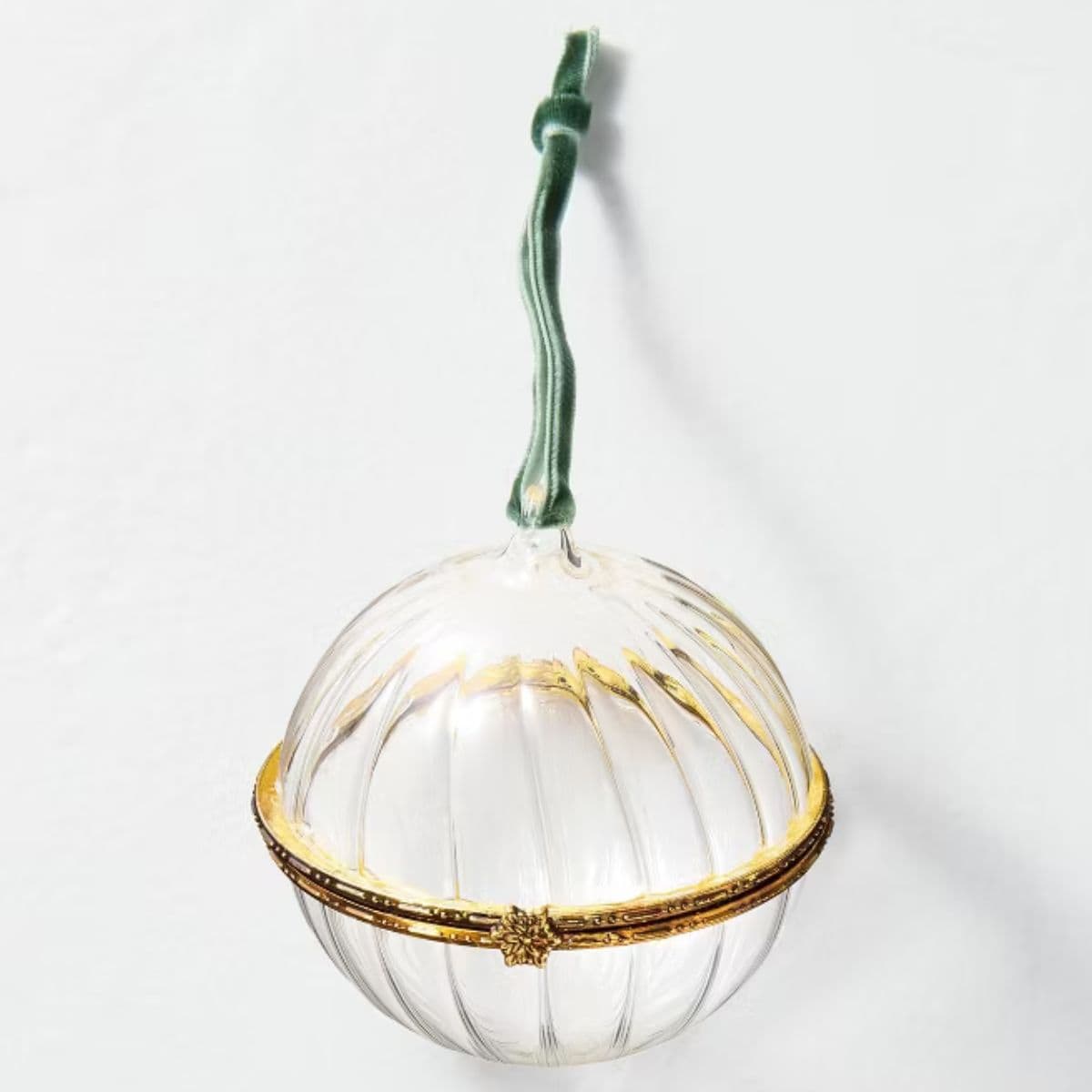Clear glass Christmas ornament with gold trim and a green velvet hanging ribbon, featuring a hinged opening around the middle.