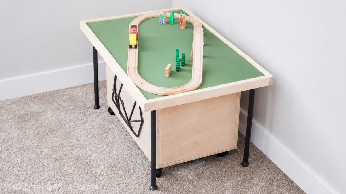 DIY wooden train table with storage underneath and a toy train track setup in a carpeted playroom corner.