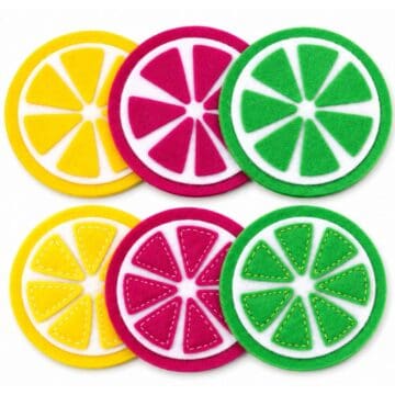 Colorful felt citrus slice coasters in yellow, pink, and green displayed in layered sets on a light gray background.