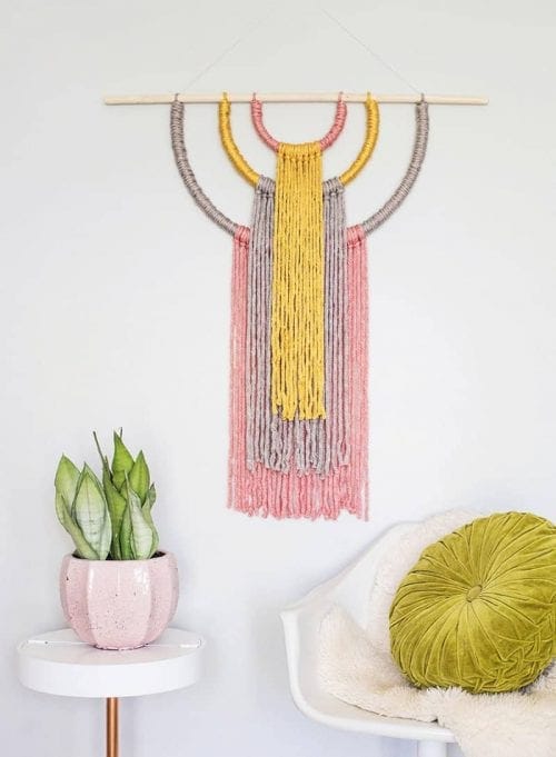 Yellow, pink, and gray yarn wall hanging craft.