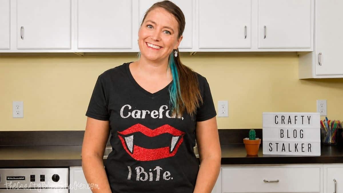 Woman wearing a black Halloween T-shirt with glitter vampire lips, fangs, and the words 