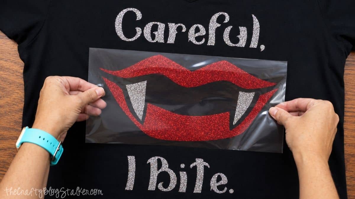 Hands positioning red glitter vampire lips over silver fangs and 