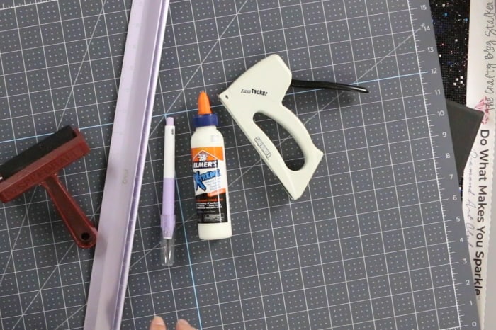Supplies used to frame diamond art; self-healing mat, furniture staples, glue,  brayer, ruler, and a cutting knife.