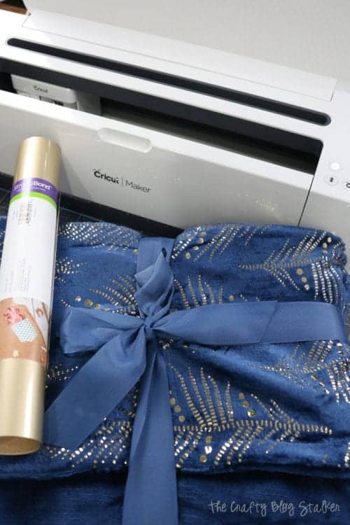 a cricut maker, gold foil iron-on and a blue and gold blanket