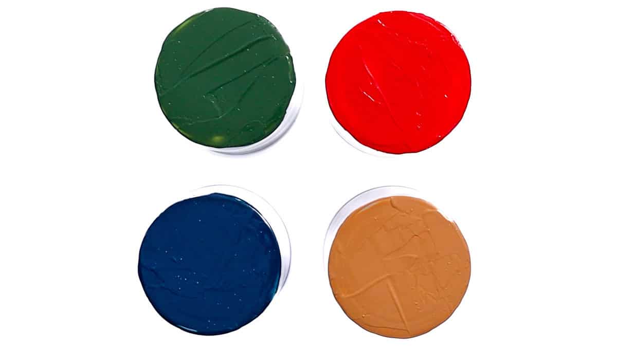 Four glass bottoms painted in different colors-green, red, blue, and tan-shown from above on a white background.