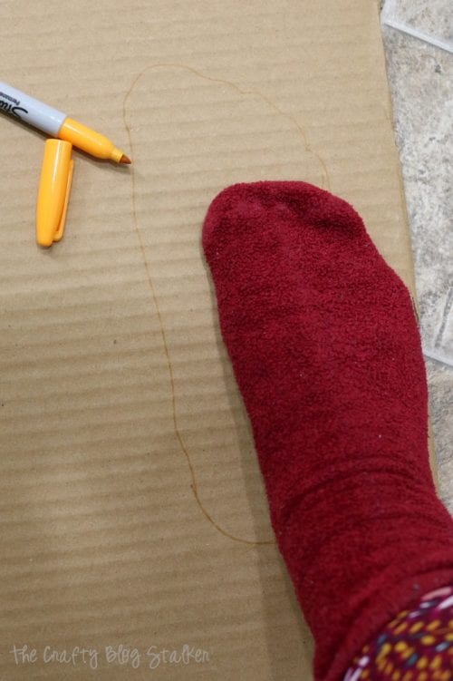 tracing a socked foot onto cardboard