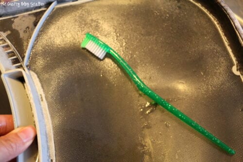 using a toothbrush to scrub the lint trap