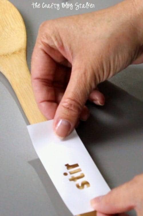 applying the vinyl stencil to the wood spoons