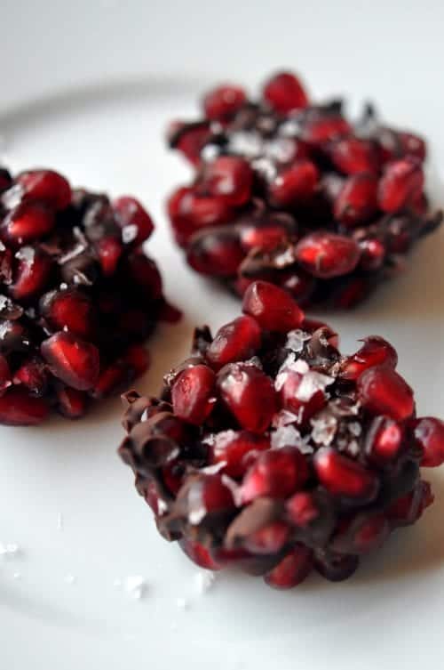 a close-up of three pomegranate and dark chocolate bites on a white background