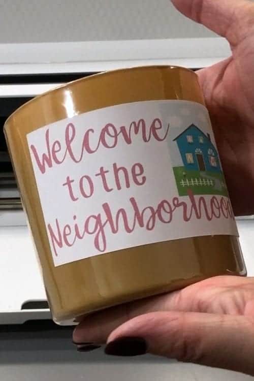 How to Print and Cut in Cricut Design Space by popular US craft blog, The Crafty Blog Stalker: image of a woman holding a candle with a Welcome to the Neighborhood label on it.