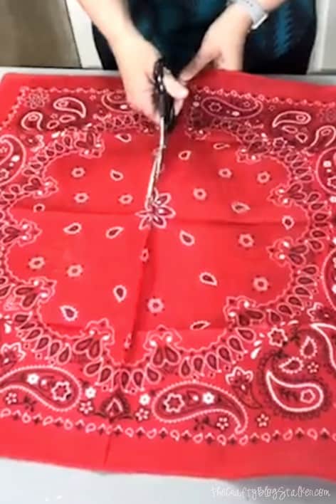 cutting red bandanas in half with a pair of scissors