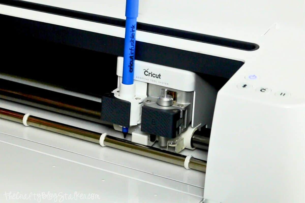 Blue Infusible Ink Marker inserted into the housing of a Cricut cutting machine.