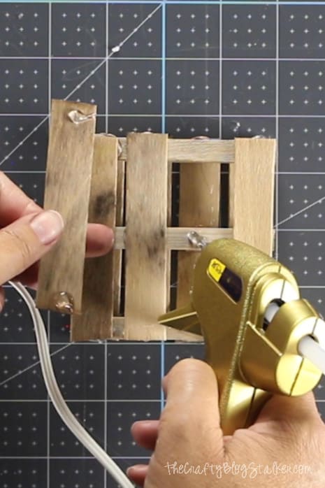 using a hot glue gun to assemble the wooden pallet coasters