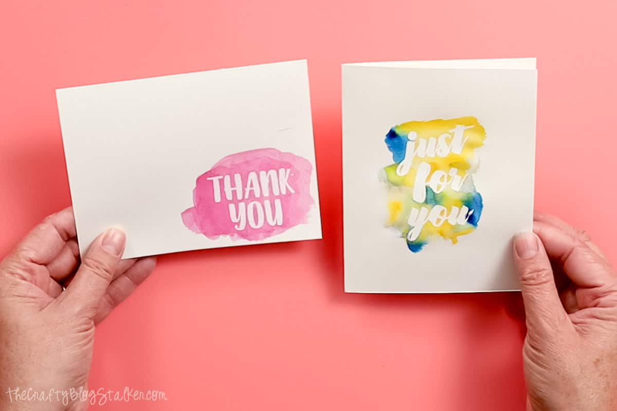 Hands holding two watercolor thank you cards.