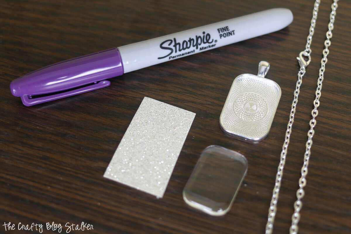 purple sharpie marker, a necklace chain and a rectangle pendant tray with glass covering