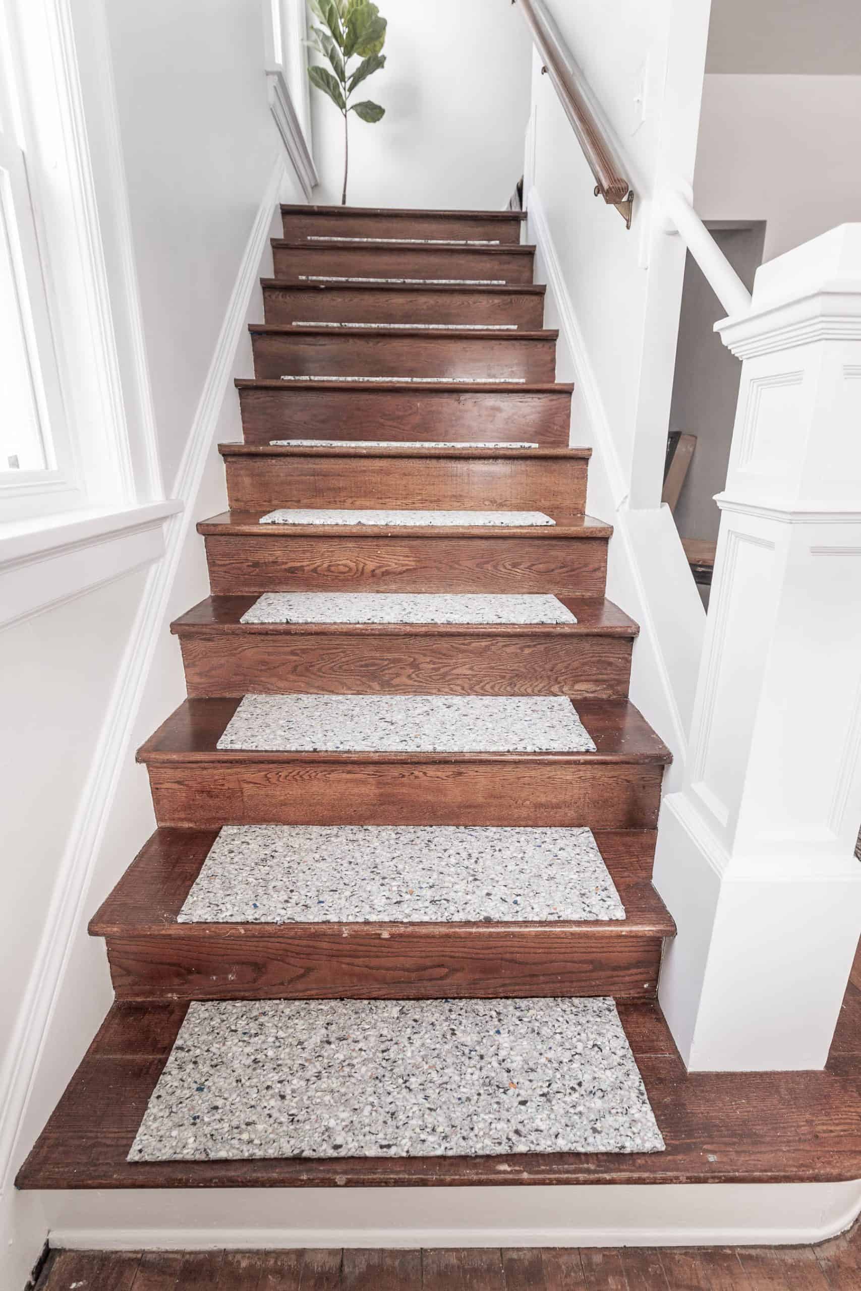 Wooden staircase with carpeted treads and white walls, interior home decor.