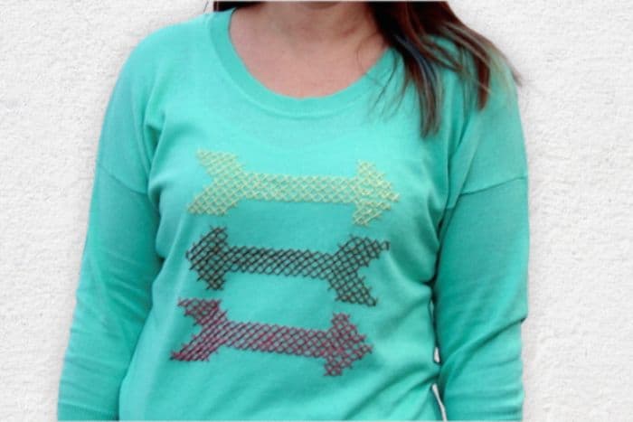 A teal sweater with cross stitched arrows.