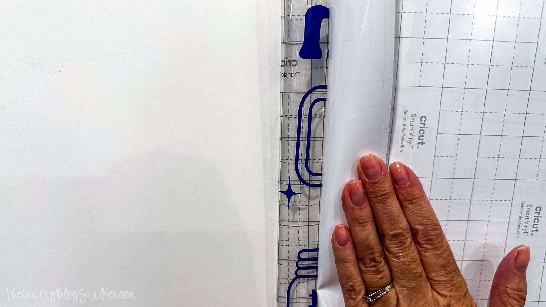 Hand holding a level tool to align a blue kitchen conversion chart vinyl decal on a wall before applying it.