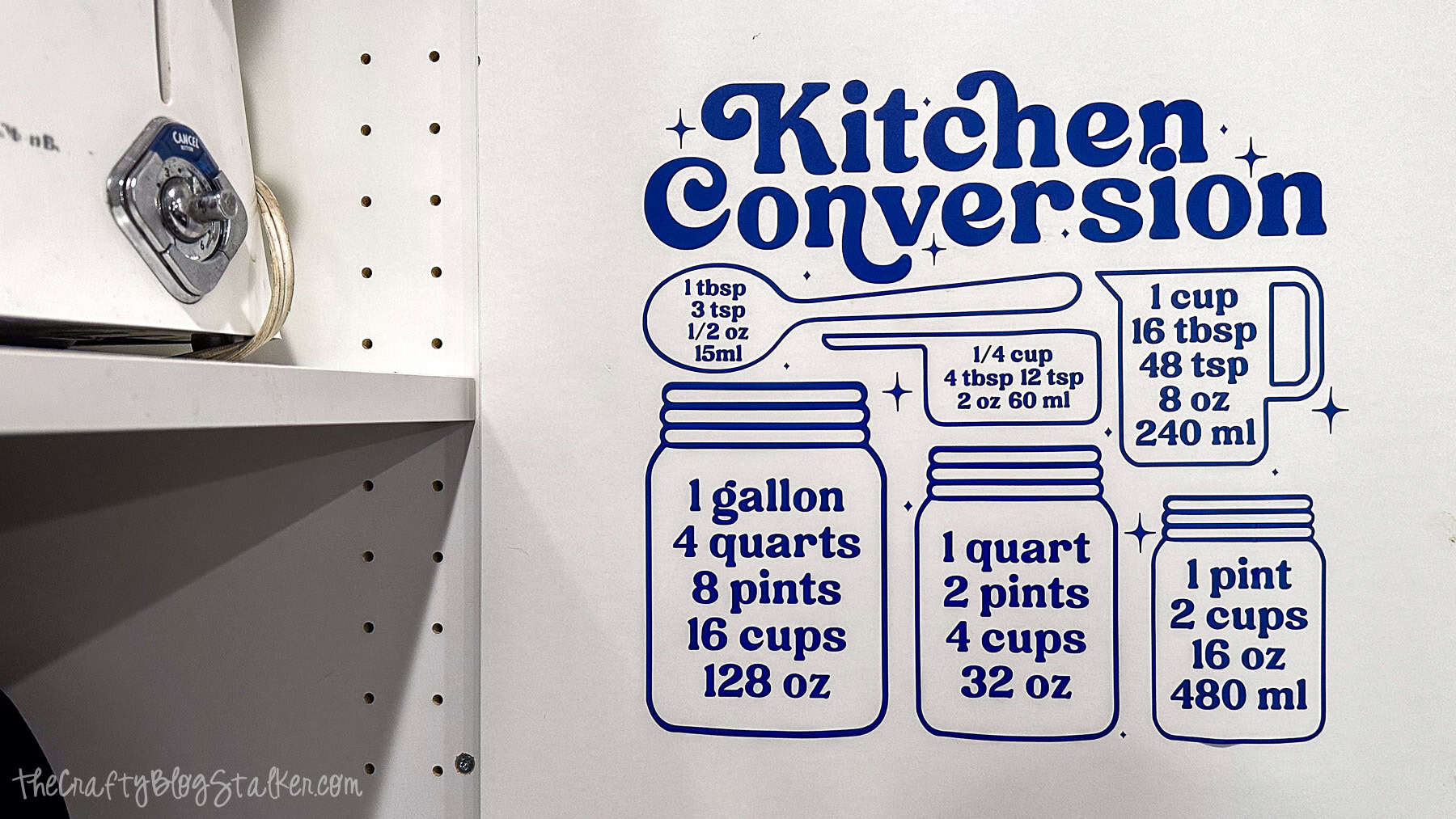Blue kitchen conversion chart decal on a wall near a stove, showing tablespoon, cup, pint, quart, and gallon measurements with illustrated jars and measuring tools.