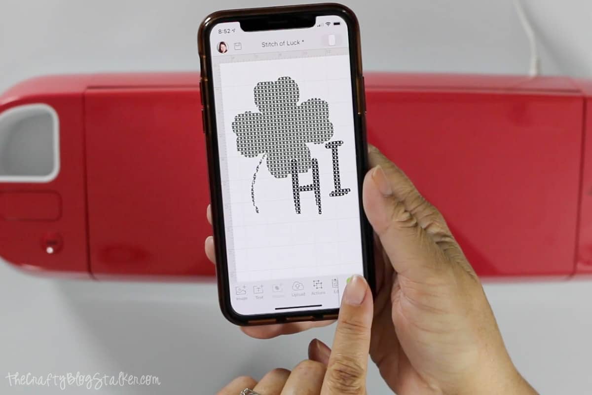 Hands holding a phone with Cricut Design Space on the screen.