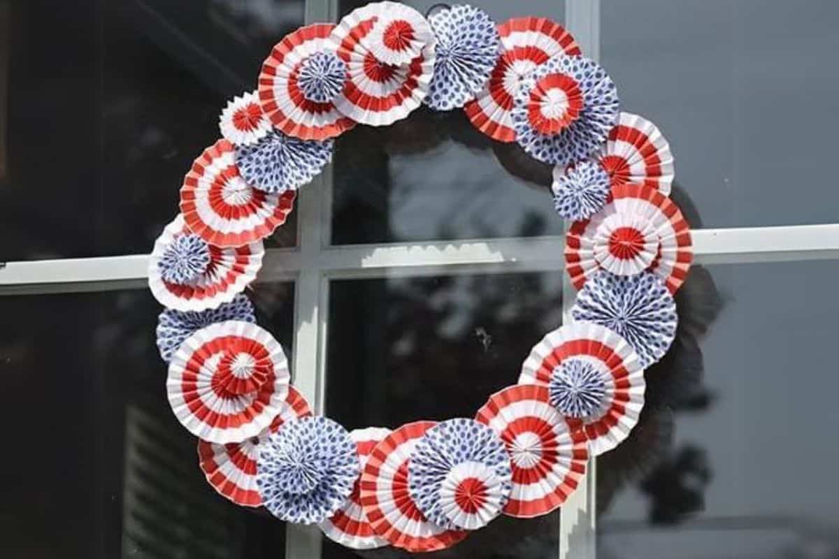 4th of July Paper Rosette Wreath hanging on a glass front door.
