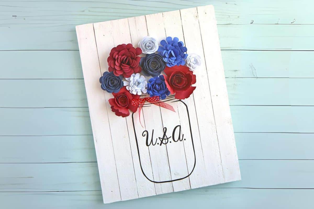 Patriotic pallet sign with Rolled Flowers in a mason jar.