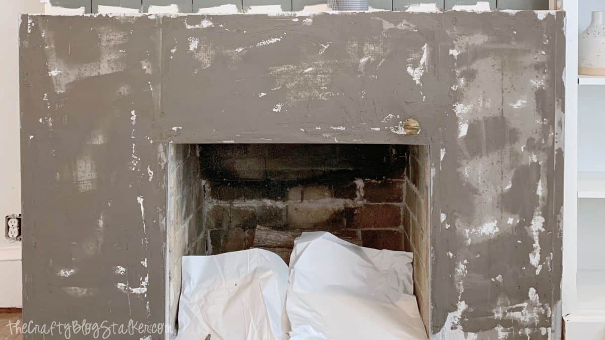 Fireplace surround coated with the first layer of concrete finish over cement backer board, creating a smooth modern surface before final sanding.