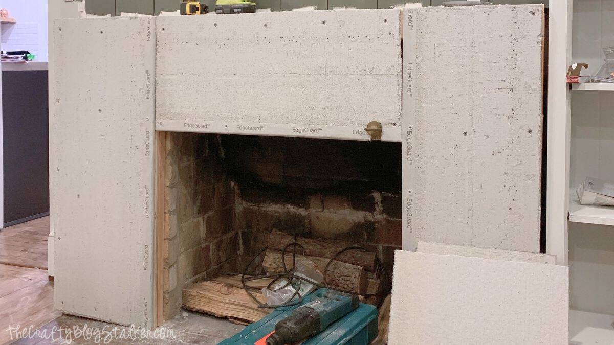 Cement backer board attached to a fireplace surround with screws, creating a heat-resistant surface before applying a concrete finish.