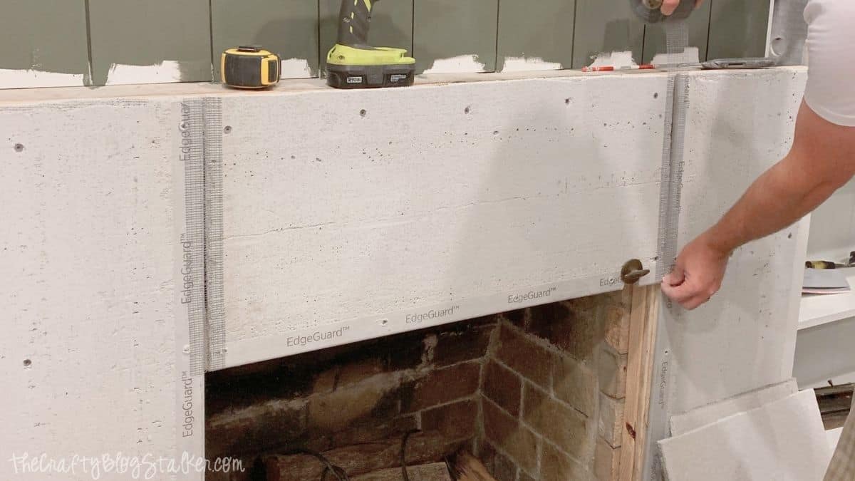 Close-up of fiberglass mesh tape applied over cement backer board seams on a fireplace surround before the concrete finish is applied.