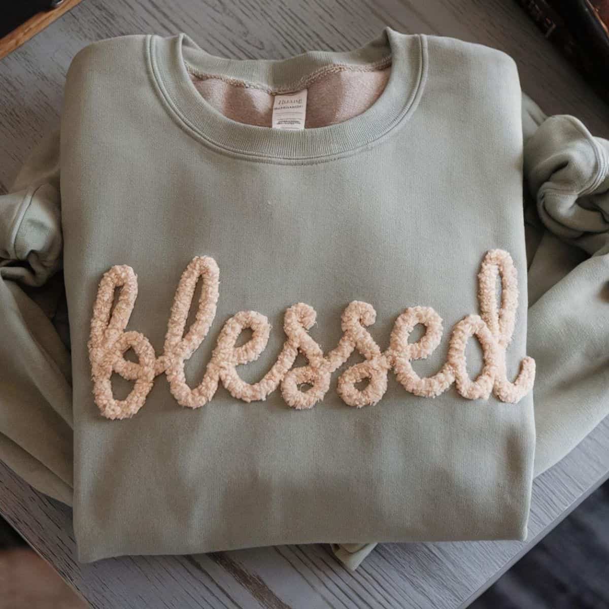 Folded sage green sweatshirt with the word 