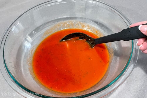 a glass bowl with pizza sauce and water