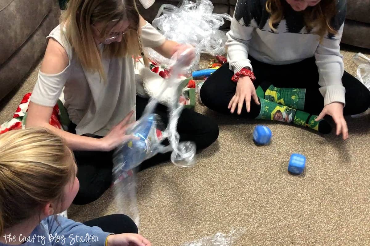 A girl unwrapping the prize ball while another girl rolls dice.