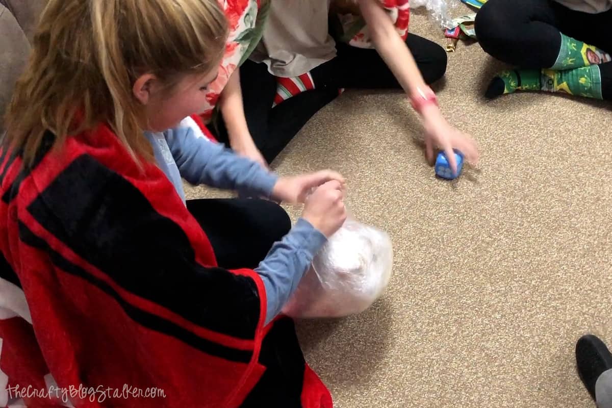 A girl trying to unwrap the prize ball.
