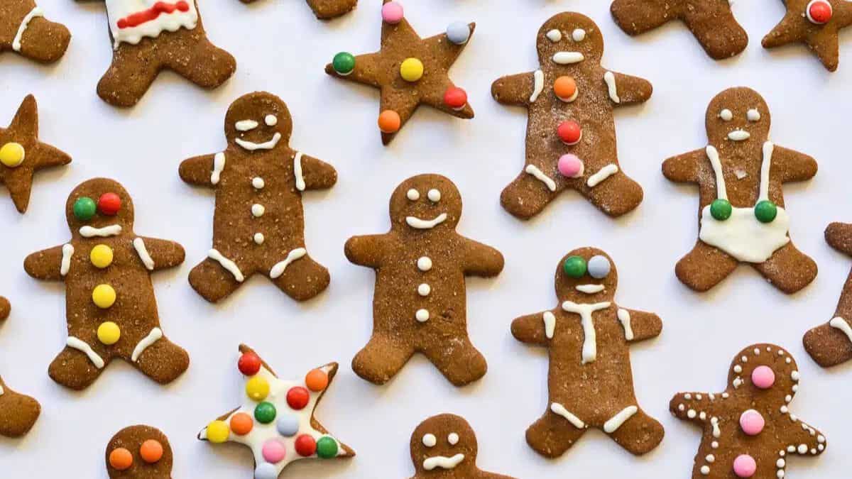 Assorted gingerbread cookies shaped like people and stars, decorated with white icing and colorful candy buttons on a white background.