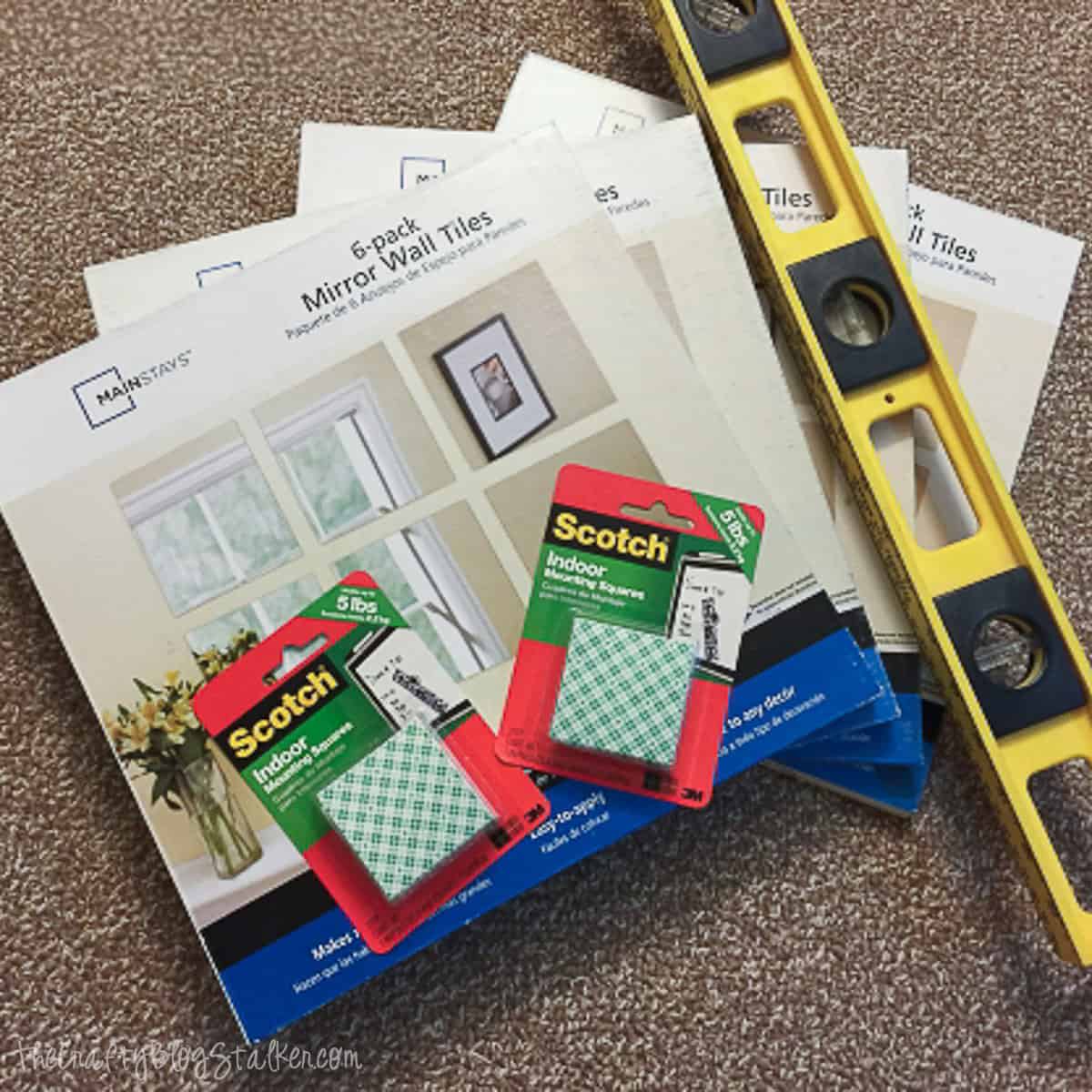 Packaged mirror wall tiles, mounting squares, and a level.