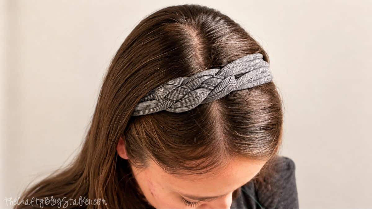 Woman wearing a braided gray t-shirt headband made from recycled fabric, styled over her brown hair.