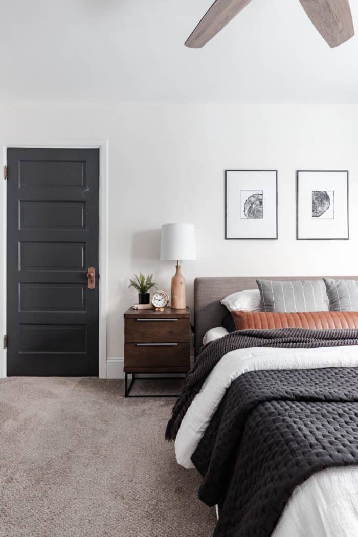 How to Make Your Bed like a Designer: Queen size bed with a modern gray headboard, white bedding, dark gray accents and a leather lumbar pillow.