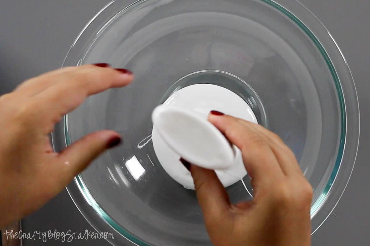 squeezing the white school glue into a glass mixing bowl