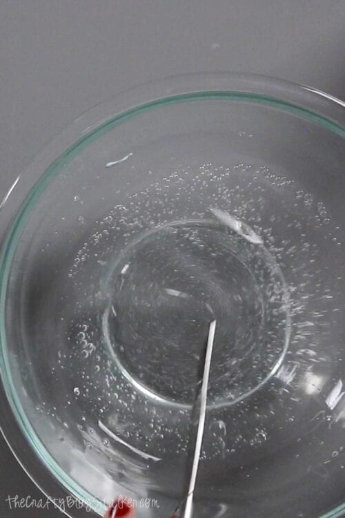 mixing water and clear school glue in a glass mixing bowl
