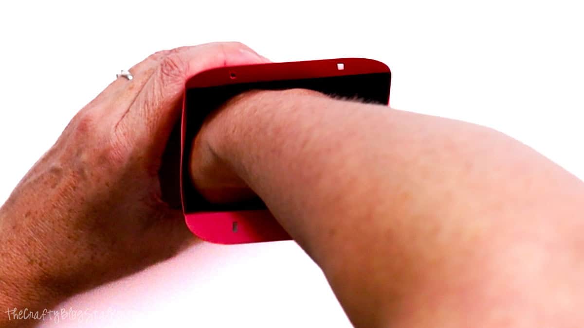 Hands pressing inside a cardstock Valentine treat bag to secure the glued bottom and shape the bag.