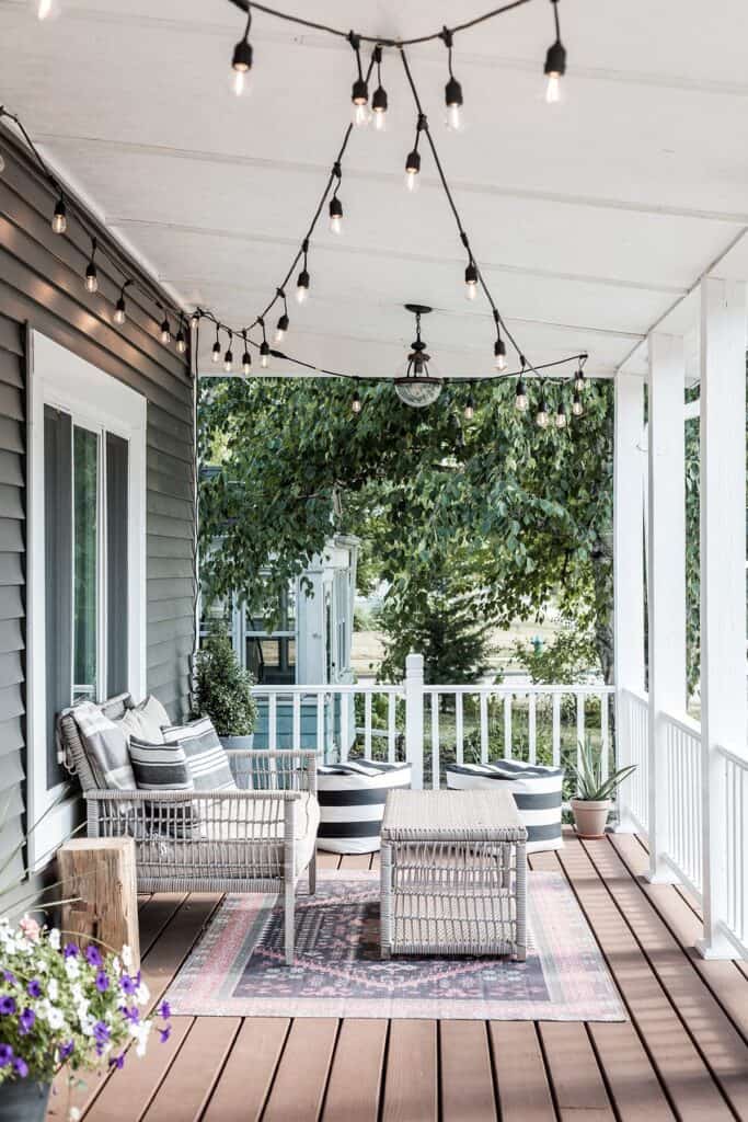 Cozy outdoor porch decorated with string lights, wicker furniture, and potted plants.