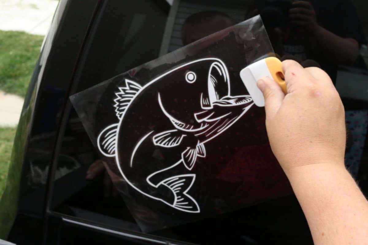 Applying a bass decal to the back window of a truck.