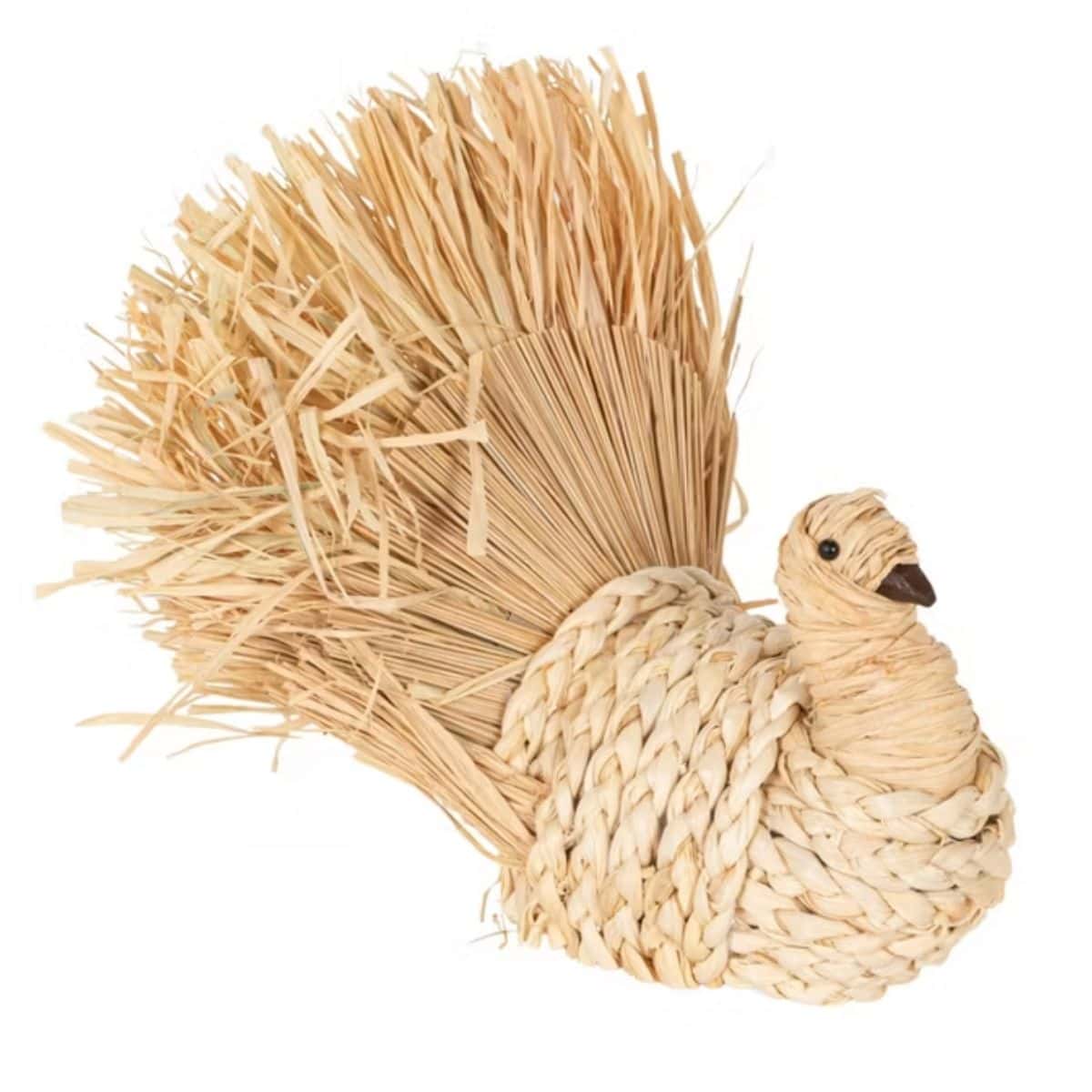 Woven corn husk turkey decoration with a braided body and large fanned straw tail on a white background.
