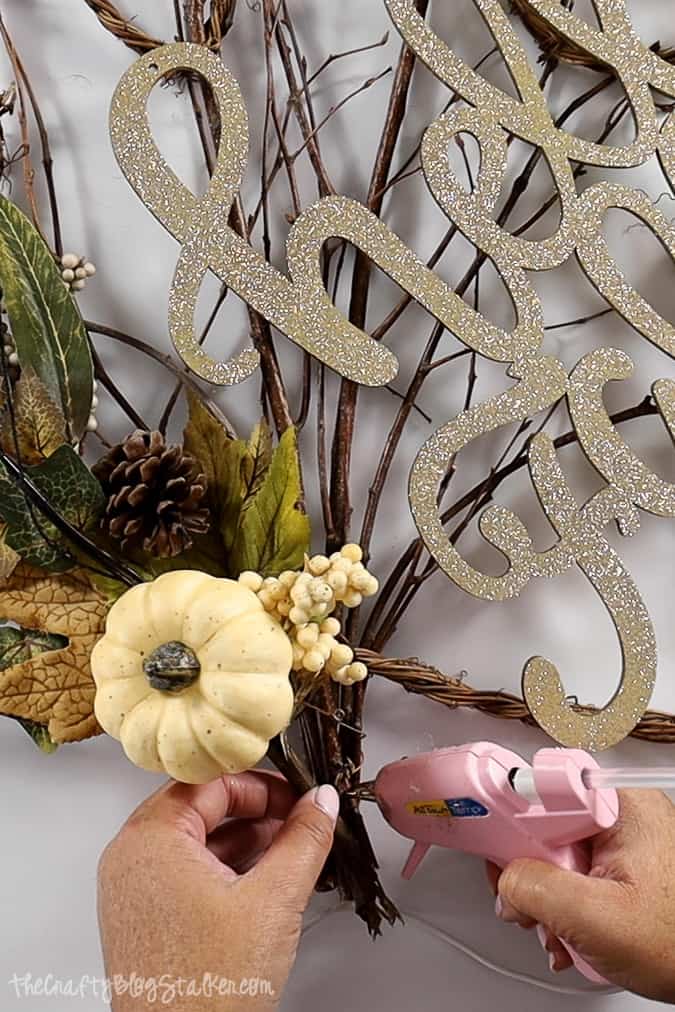 using a hot glue gun to secure fall floral pick in place