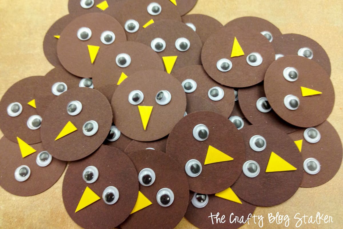 A pile of brown circles with yellow beaks and google eyes to make paper turkeys.