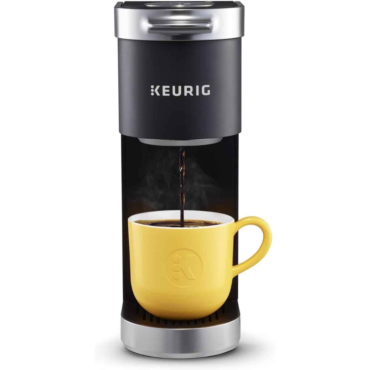 Black Keurig single-serve coffee maker brewing coffee into a yellow mug.