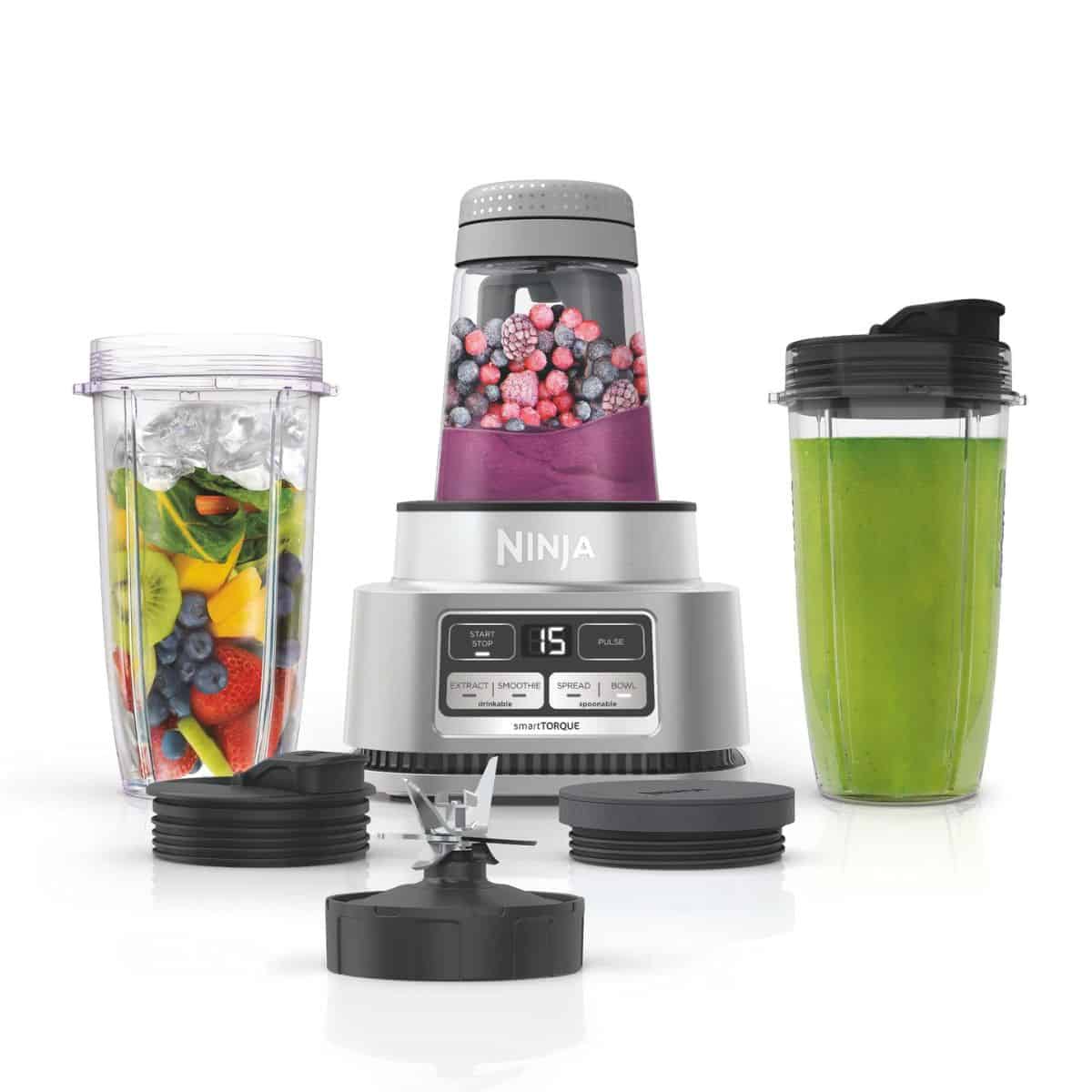 Ninja smoothie bowl maker and blender with fruit-filled cups, blending blades, and multiple to-go lids for smoothies and shakes.