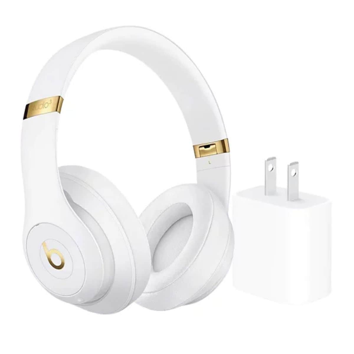 White Beats Studio3 wireless Bluetooth headphones with gold accents shown beside a white wall charger on a plain white background.