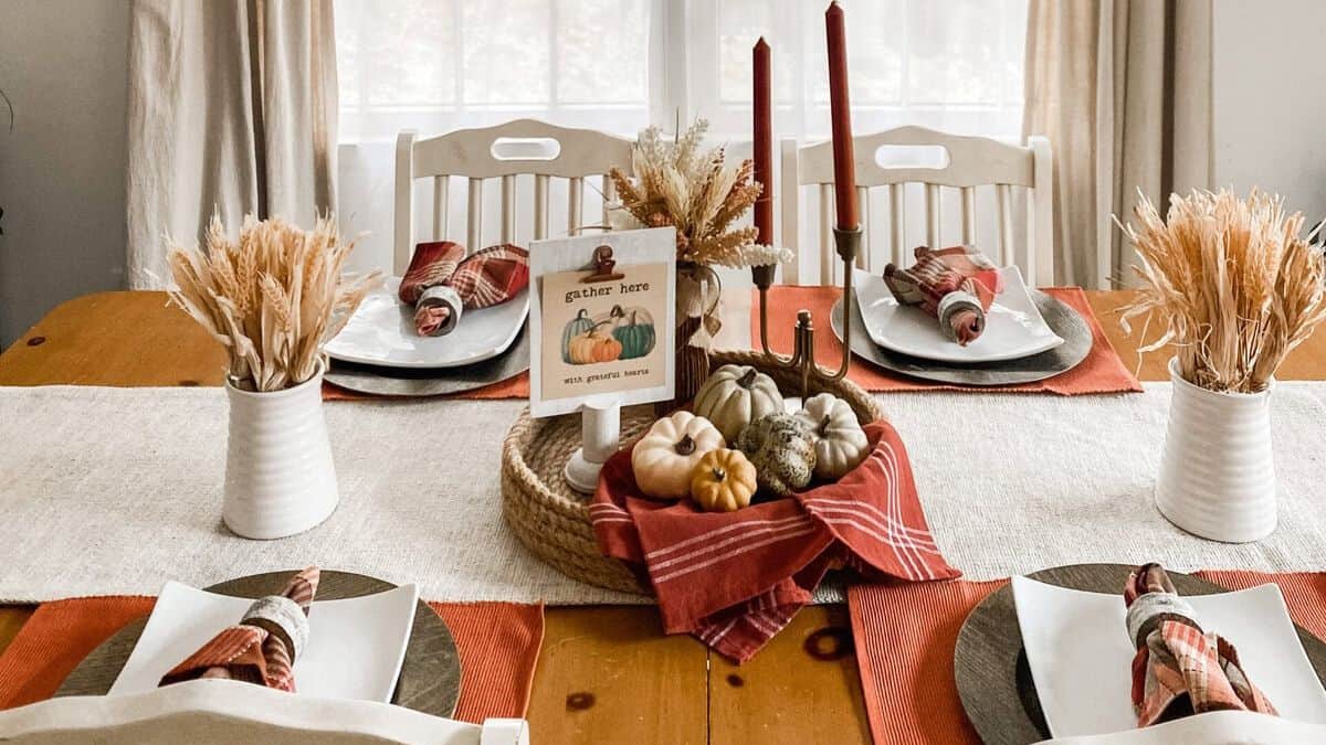 Farmhouse Thanksgiving table with mini pumpkins, red napkins, wheat centerpieces, and a
