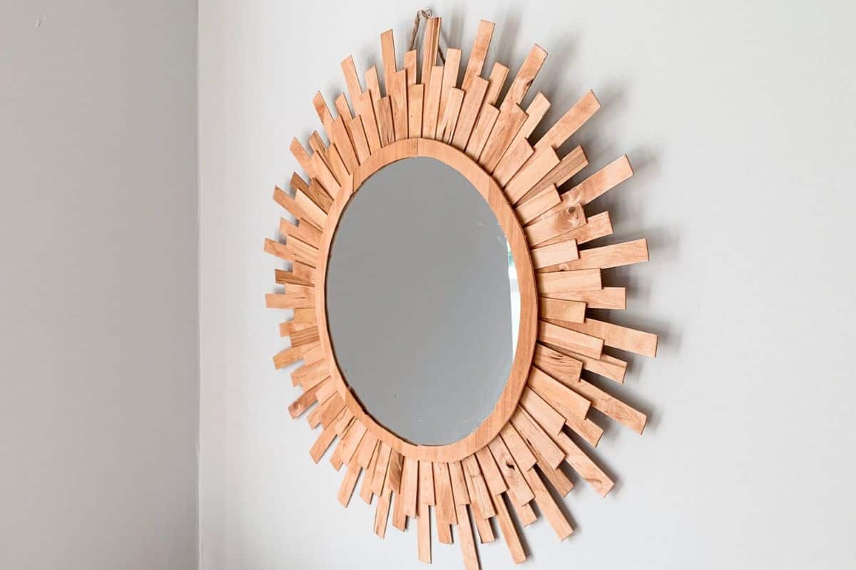 DIY Sunburst mirror hanging on a gray wall.
